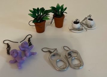 pictured: four pairs of earrings on a white desk.